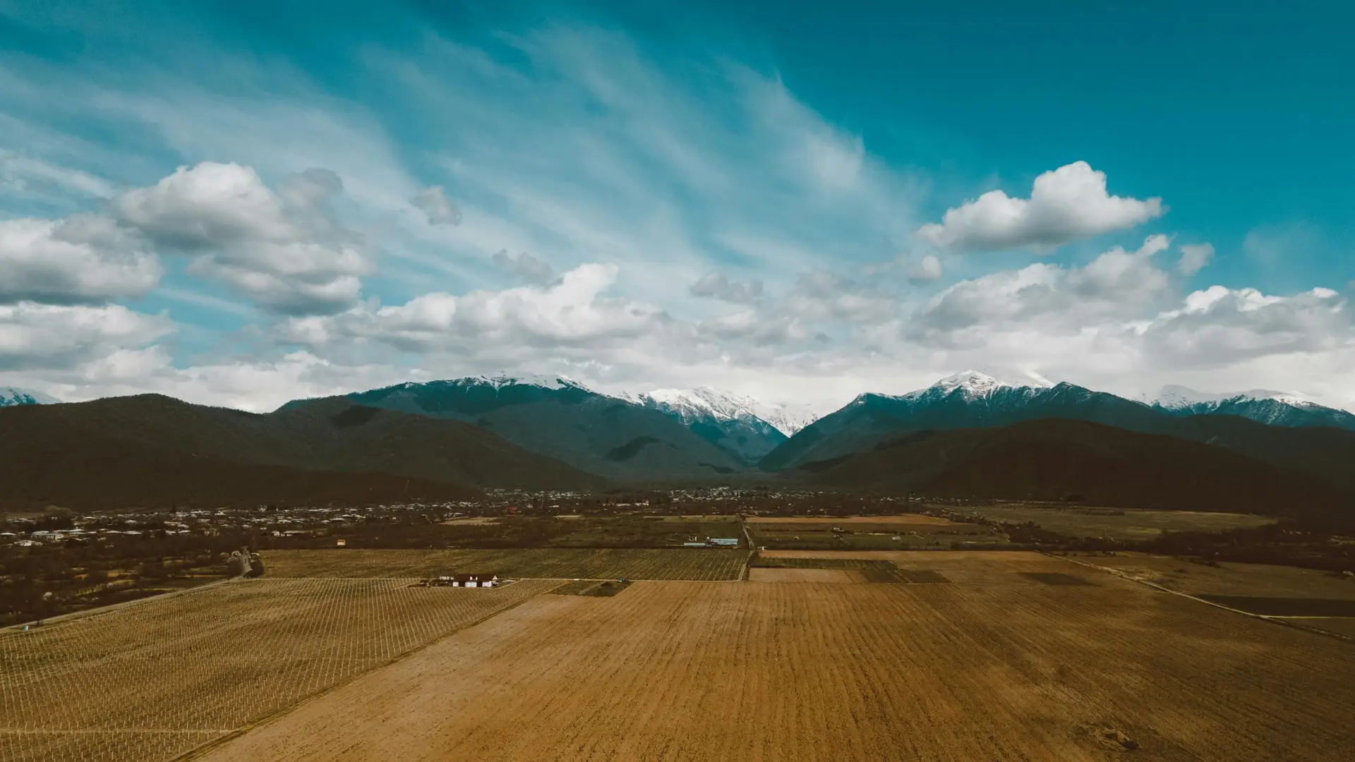 pexels-photo-7539809-7539809 Breathtaking aerial view of rural fields against snowy mountains and blue sky.